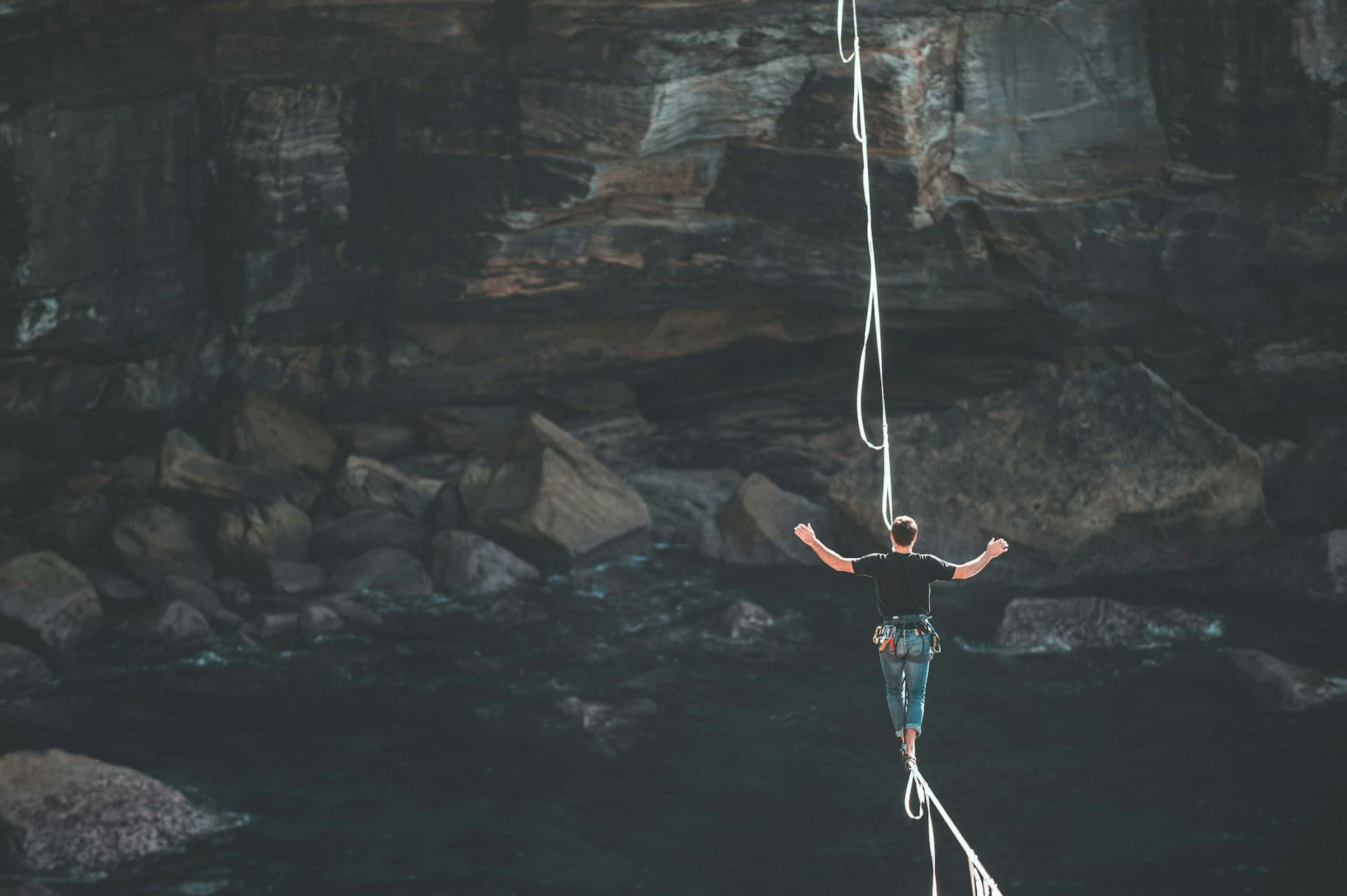 Silhouette of a person walking on a high slackline across a canyon, illustrating the balance and risk involved in Madrid real estate investment.